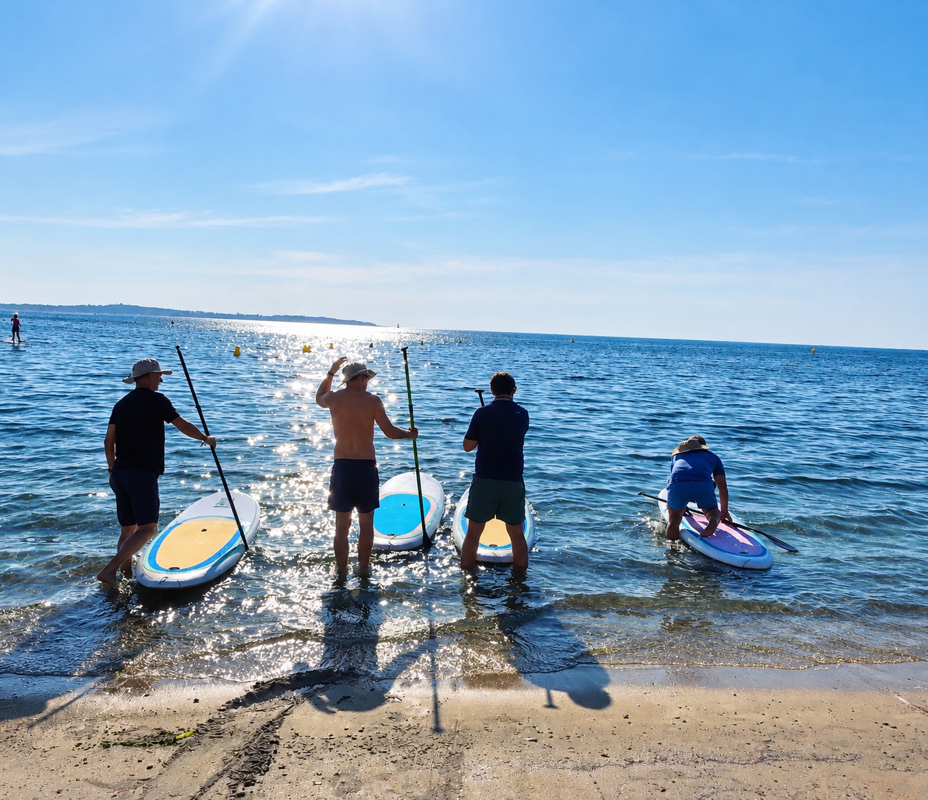 Des participants mettent leurs paddles à l’eau depuis la plage.