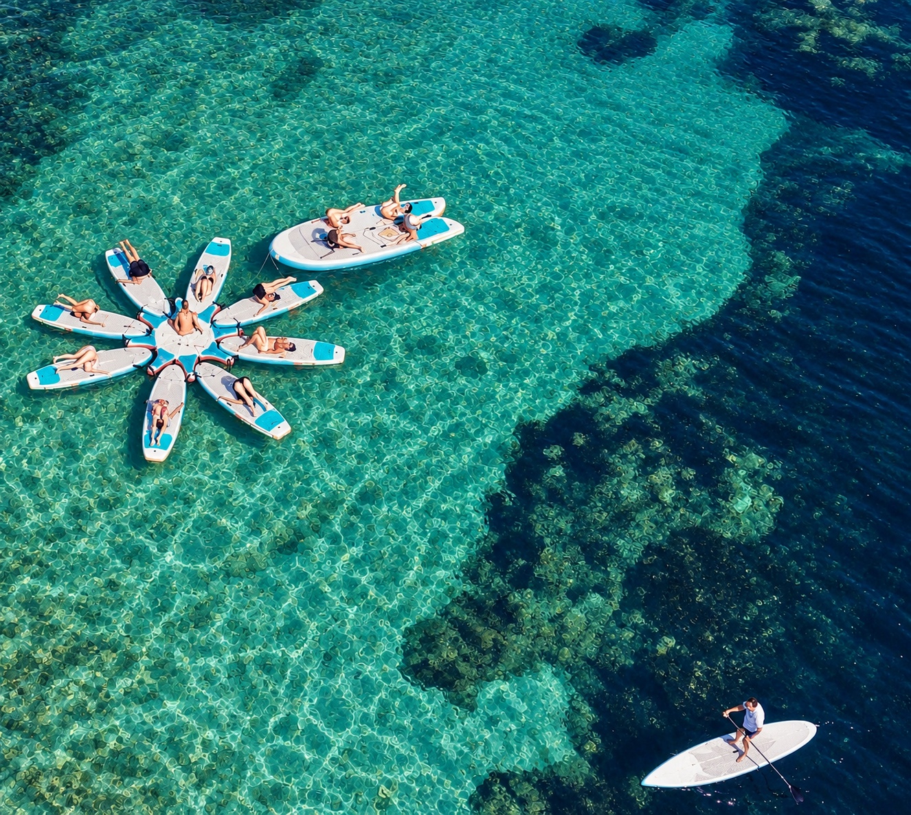 Aerial view of a paddleboard yoga session on turquoise water in Cannes